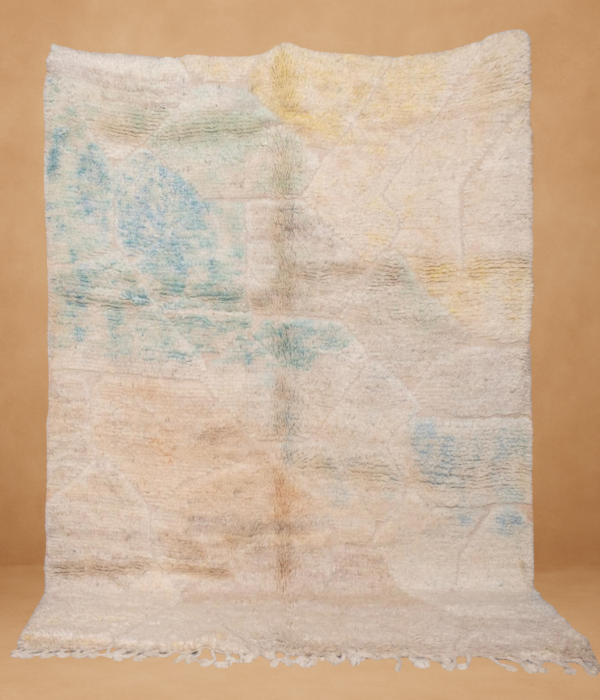 Beni Ouarain rug with a soft, creamy white base and delicate pastel accents in blue, green, yellow, and peach. The subtle, faded geometric pattern blends seamlessly into the plush wool texture, creating a calm, dreamy aesthetic. Displayed vertically with gentle fringe on the bottom, set against a warm beige backdrop.