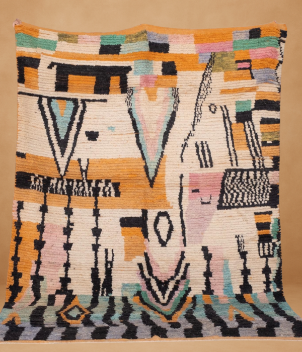 Boujad rug with an abstract, tribal-inspired design featuring bold black shapes and soft pastel tones of peach, mint, lavender, and mustard on a cream background. The handwoven wool texture adds depth to the intricate, symbolic patterns. Displayed vertically with subtle fringe, set against a warm neutral backdrop