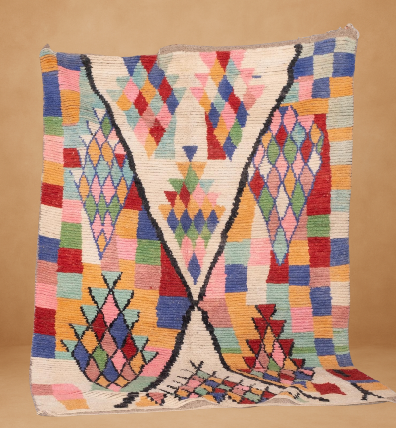 Vibrant Boujad rug featuring multicolored diamond and checkered patterns in shades of red, pink, blue, green, yellow, and orange. The bold geometric design is framed by black contour lines, creating a dynamic V-shaped composition. Handwoven in wool and displayed vertically against a neutral background.