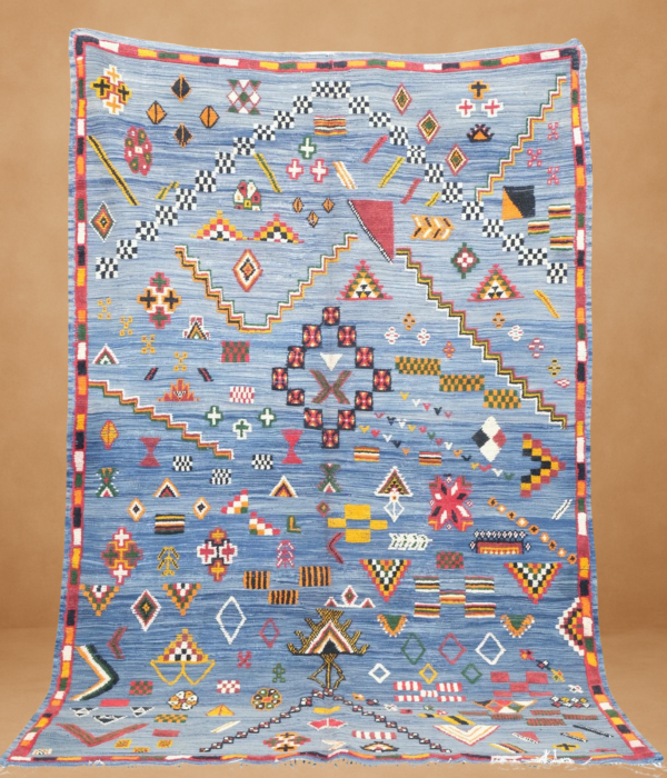 Mesmerizing Taznaght rug with intricate tribal motifs and vibrant colors on a serene blue background.