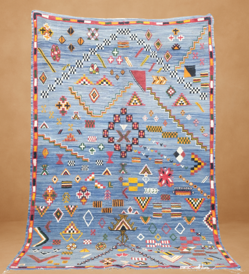 Mesmerizing Taznaght rug with intricate tribal motifs and vibrant colors on a serene blue background.