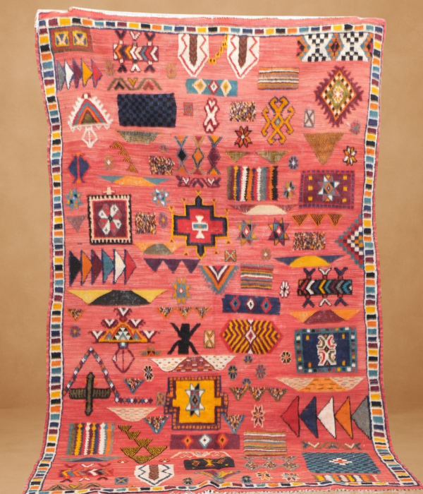 Stunning Kilim rug with a vibrant coral-red background, adorned with multicolored tribal motifs.