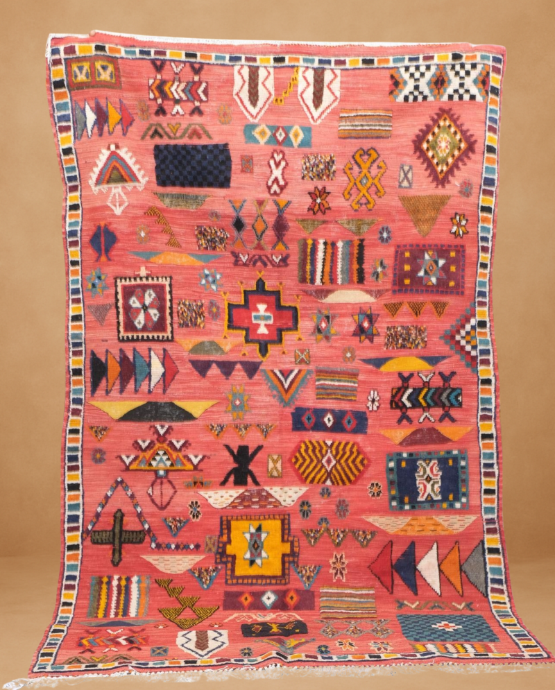Stunning Kilim rug with a vibrant coral-red background, adorned with multicolored tribal motifs.